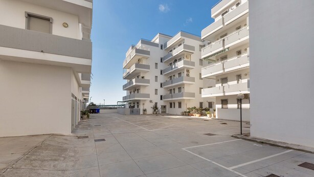 A multi-story residential building with balconies, a courtyard, and a clear sky. - Appartamento Baiabella (Gallipoli)