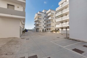 Een meerlaags woongebouw met balkons, een binnentuin en een heldere lucht.