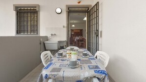 A small dining area with a table set for two, a window with bars, and a view into the kitchen. - Appartamento Baiabella (Gallipoli)