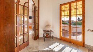 A hallway with a wooden door, a glass door, and a small table with a lamp. - Villa Alice (Porto Cesareo)