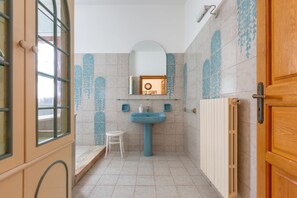 A bathroom with a blue sink, a mirror, and tiled walls. - Villa Alice (Porto Cesareo)