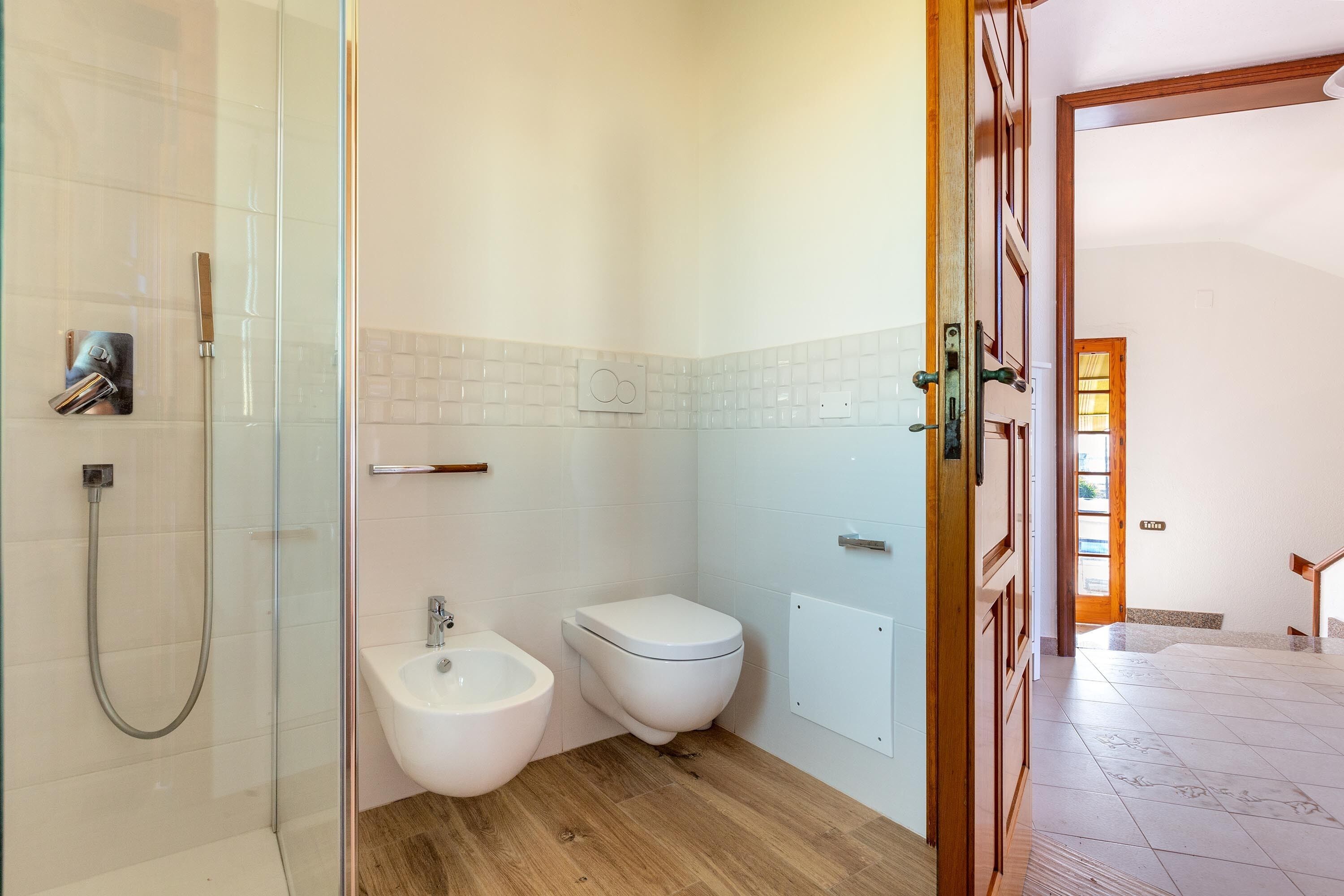 A bathroom with a glass-enclosed shower, a bidet, and a toilet.