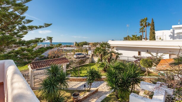 A residential area with a white building, a paved driveway, and a car parked in front. - Villa Alice (Porto Cesareo)