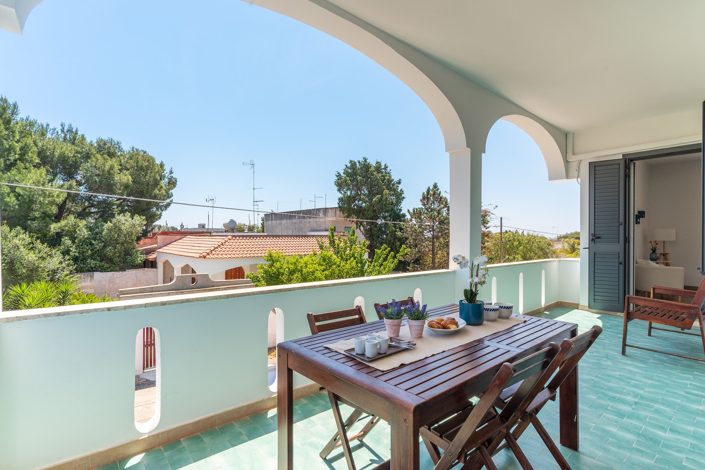 Ein Balkon mit Holztisch, Stühlen und Blumentöpfen.