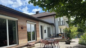 A house with a patio area featuring a table and chairs, a potted plant, and a view of the surrounding landscape. - Beautiful and cozy house in the middle of nature. (Niedereschach)
