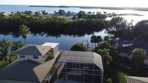 A residential area with houses near a body of water, featuring a large glass structure on one property. - LUXURIOUS FIVE BEDROOM FLORIDA ESCAPE (Port Charlotte)
