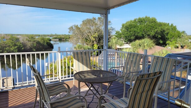 A covered outdoor area with a view of a lake, featuring a table and chairs. - LUXURIOUS FIVE BEDROOM FLORIDA ESCAPE (Port Charlotte)