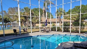 A pool area with a clear view of the surrounding landscape, including palm trees and a building in the background. - LUXURIOUS FIVE BEDROOM FLORIDA ESCAPE (Port Charlotte)
