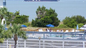 A large MSC cargo ship on the water, with a pool area and umbrellas in the foreground. - Savannah Beach & Racquet Club 303A (Tybee Island)