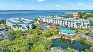A hotel with multiple buildings, a parking lot, and a body of water. - Savannah Beach & Racquet Club 303A (Tybee Island)
