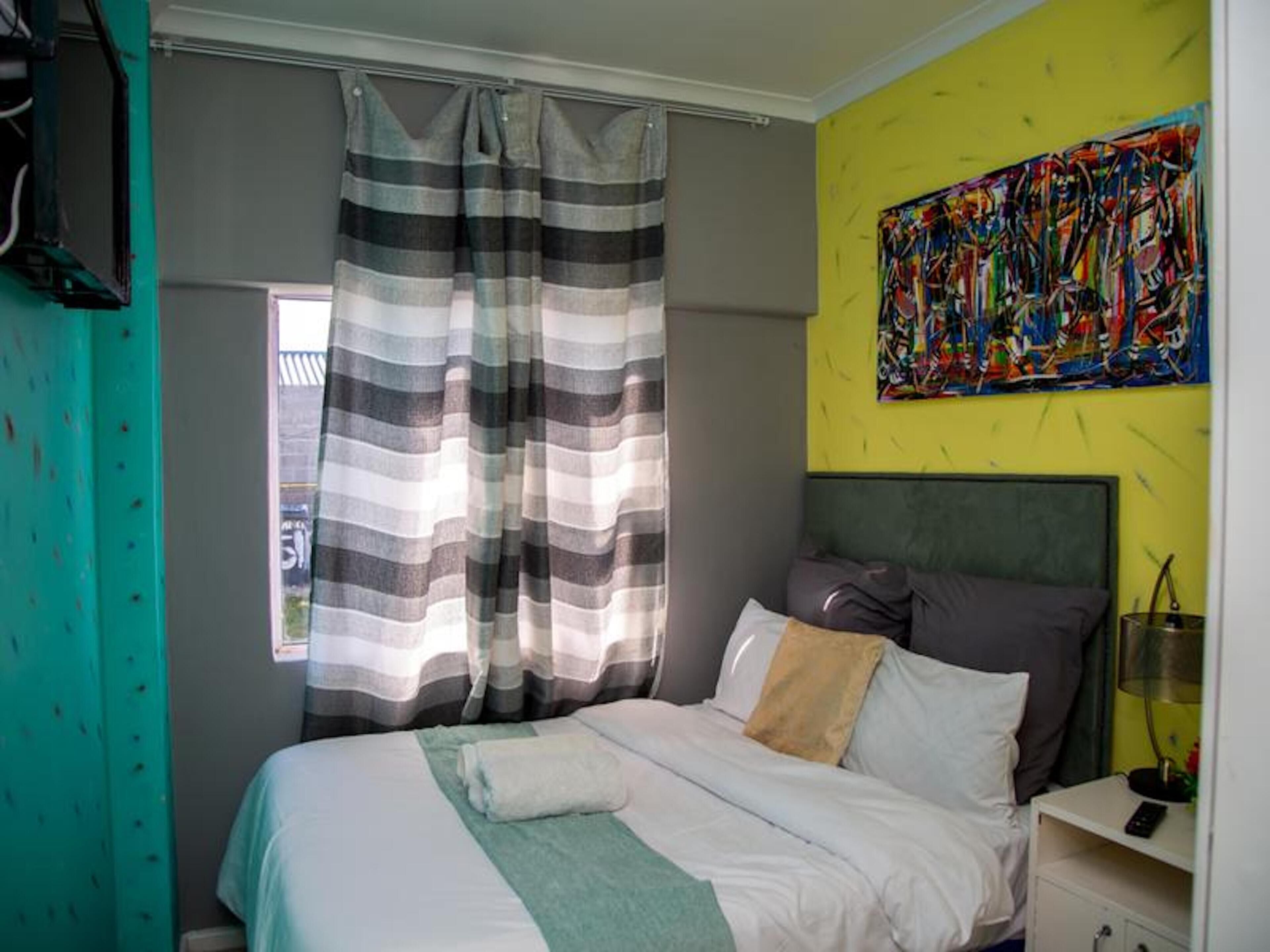 Ein Schlafzimmer mit Bett, Vorhängen, einem Bild und einem Nachttisch.