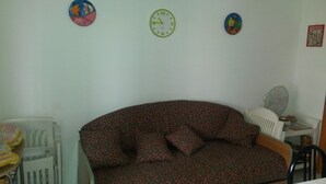Una habitación con un sofá, una mesita, una silla y un radiador.