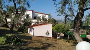 A white building with a red roof, surrounded by trees and greenery.