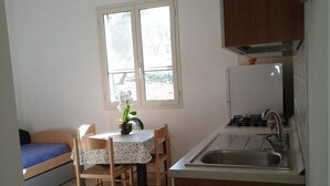 A small kitchen with a dining table, chairs, a gas stove, and a sink.