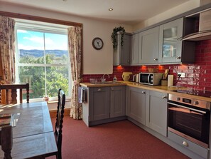 A kitchen with grey cabinets, a microwave, a toaster, and a red-tiled backsplash.