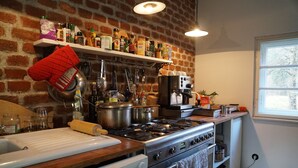 Une cuisine avec un mur en briques, un plan de travail en bois, ainsi que divers ustensiles et appareils de cuisine.