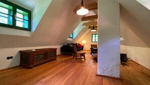 Une pièce de style loft avec un plancher en bois, un canapé, un fauteuil et un meuble.
