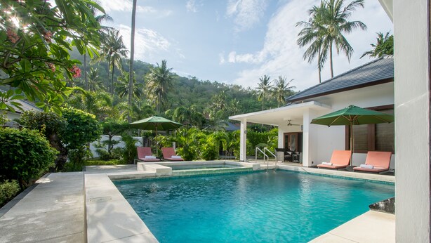 A pool area with lounge chairs and umbrellas, surrounded by lush greenery and palm trees. - Lombok From Your Private Villa Sepuluh (Senggigi)