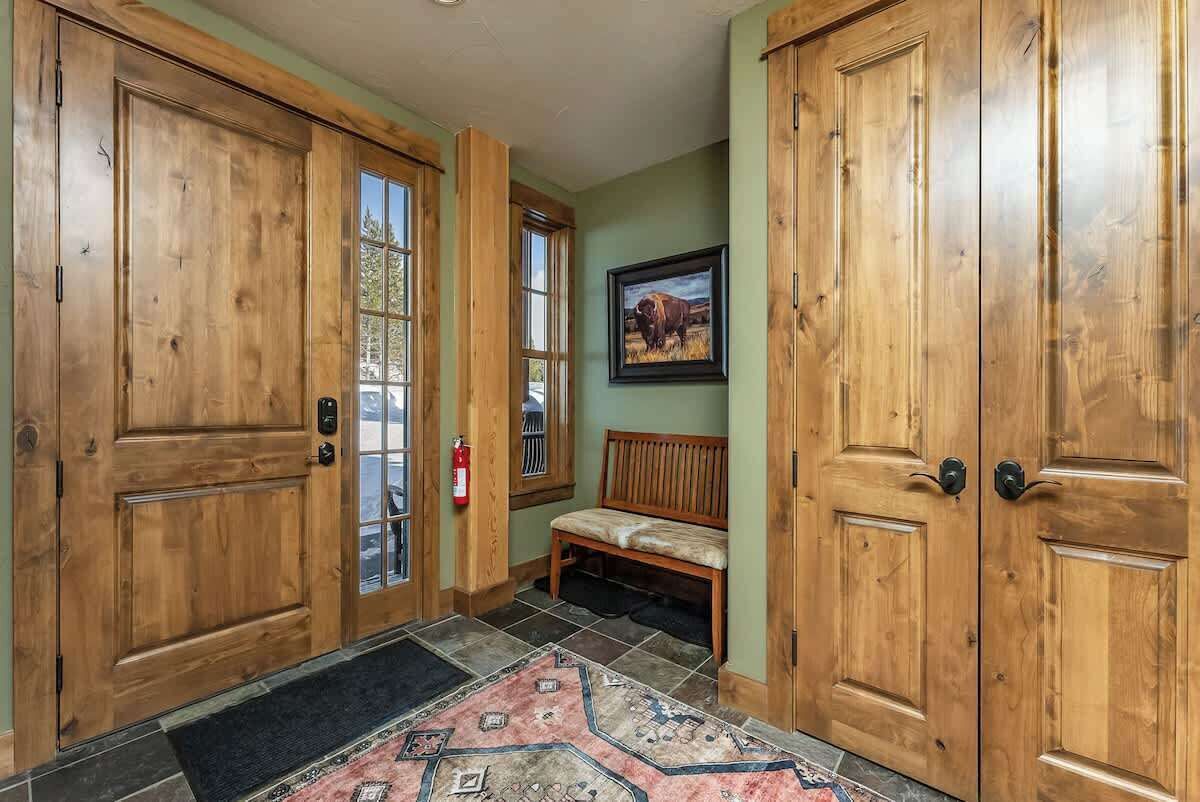 A wooden door with a glass panel, a bench, and a framed picture on the wall.