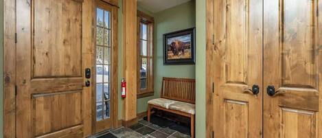 A wooden door with a glass panel, a bench, and a framed picture on the wall.