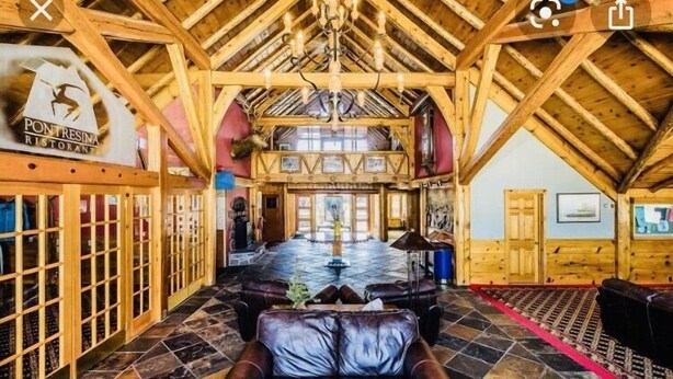 A spacious lobby with a high wooden ceiling, a central fountain, and leather seating areas.