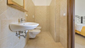 Un baño con un lavamanos, dos inodoros y un espejo.