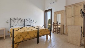 Un dormitorio con cama, un armario de madera y una puerta que da a un balcón.