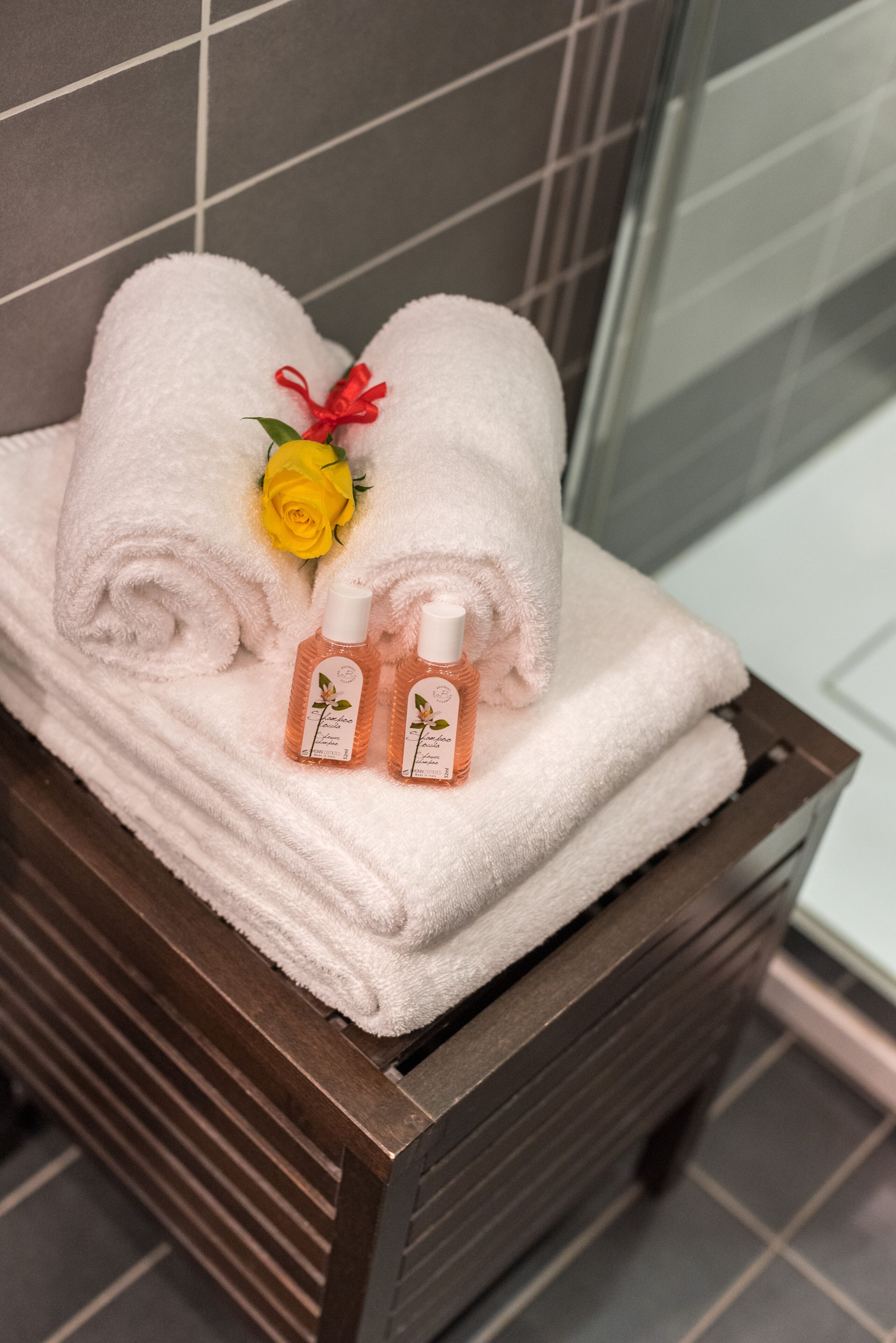 A wooden bath tray with neatly folded white towels and two bottles of lavender-scented lotion.