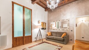 Sala de estar com sofá cinza, luminária de chão, espelho e porta de correr com moldura de madeira.