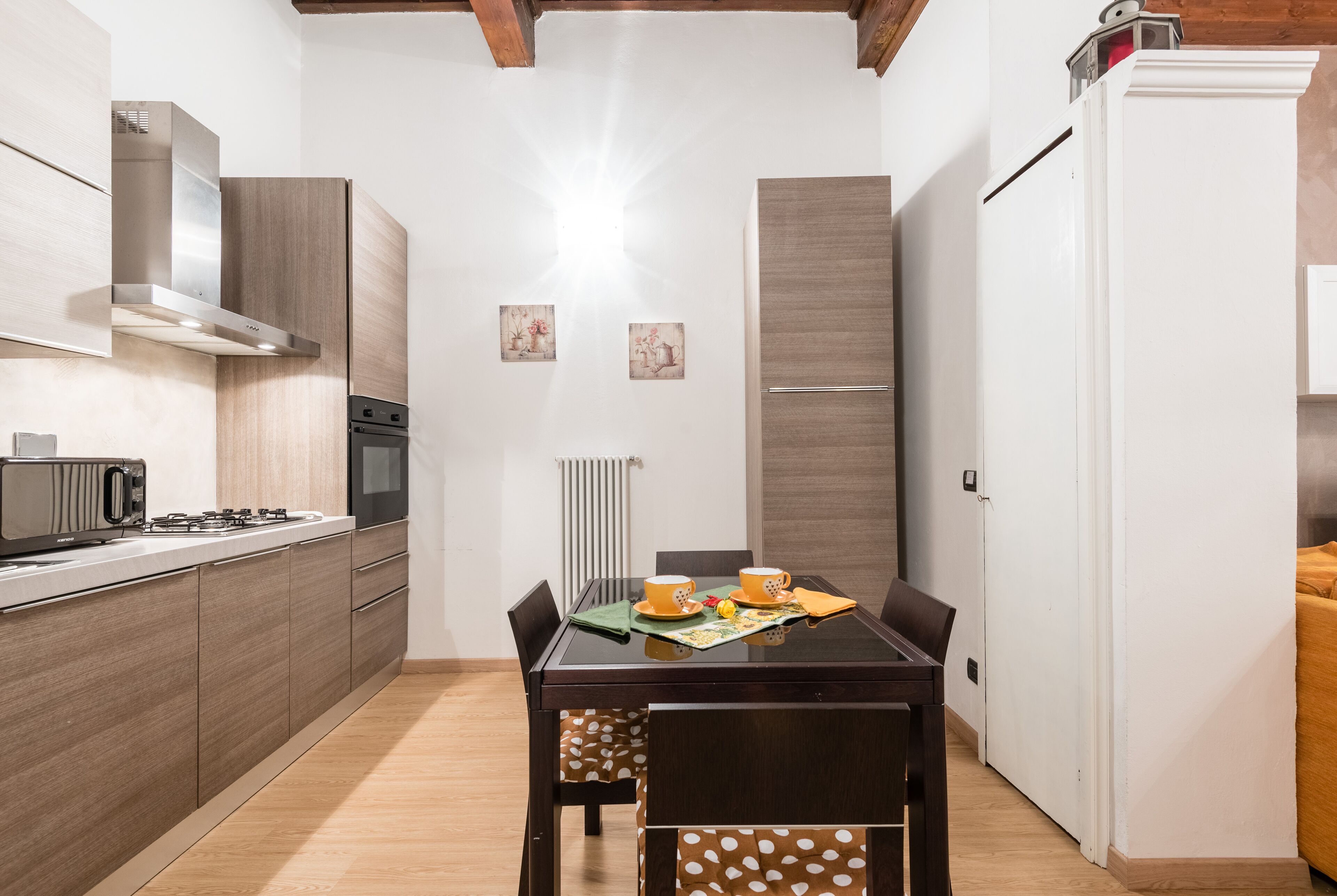 A compact kitchen with a dining area, featuring a stove, microwave, and a refrigerator.
