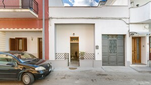Un edificio de dos pisos con un coche estacionado adelante.