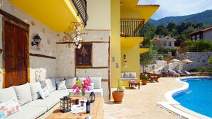 A poolside area with a wooden table, cushions, and a potted plant. - Room-authentic Boutique Hotel (Fethiye)