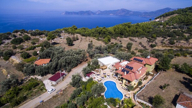 An aerial view of a property with a swimming pool, solar panels, and a road. - Room-authentic Boutique Hotel (Fethiye)