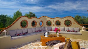 An outdoor seating area with a stone floor, a wooden coffee table, and a sofa with cushions. - Room-exclusive Boutique Hotel 4 (Fethiye)