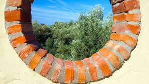 A circular brick window with a clear blue sky and green foliage visible through it. - Room-exclusive Boutique Hotel 4 (Fethiye)