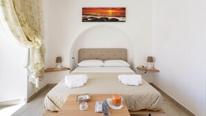 Une chambre à coucher avec un lit, deux lampes de chevet, une table de chevet avec une bougie, un tableau encadré et une fenêtre avec des rideaux.