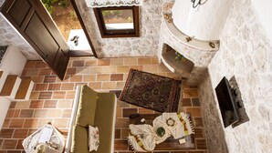 A cozy room with a stone wall, a wooden door, a small window, a patterned rug, a sofa, and a table with a teapot and cups. - Room-exclusive Boutique Hotel 3 (Fethiye)