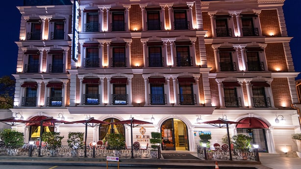 Un hôtel à plusieurs étages, de style architectural classique, avec une entrée imposante surmontée d’un auvent et d’une enseigne indiquant le nom « Hôtel ».