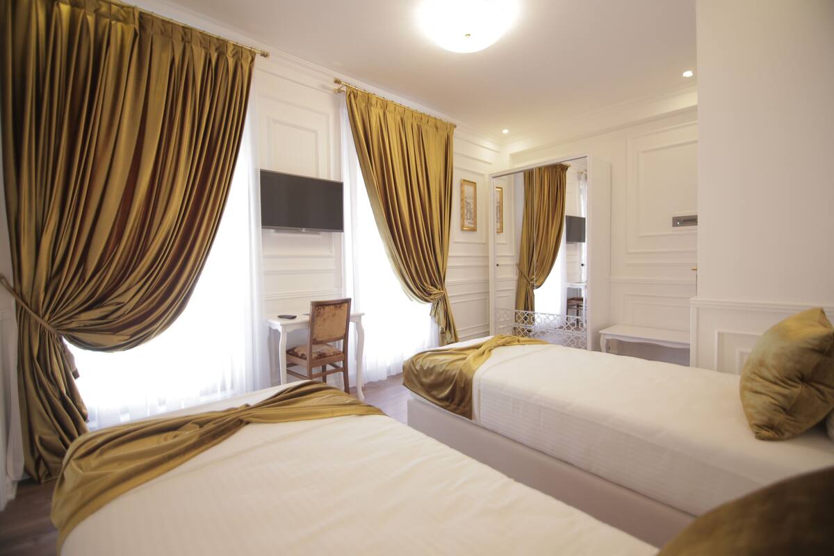 Ein Hotelzimmer mit zwei Betten, einem Schreibtisch und einem Stuhl.