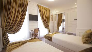 Quarto de hotel com duas camas, uma mesa e uma cadeira.