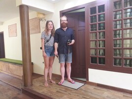 Un pasillo con piso de madera, una puerta con paneles de vidrio y un pilar de madera.