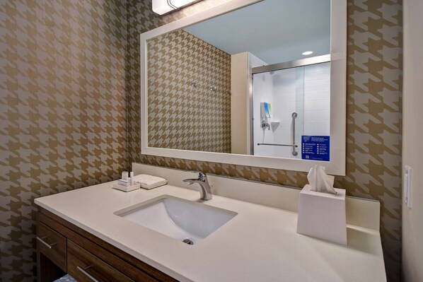 A bathroom with a white sink, a mirror, and patterned wallpaper.