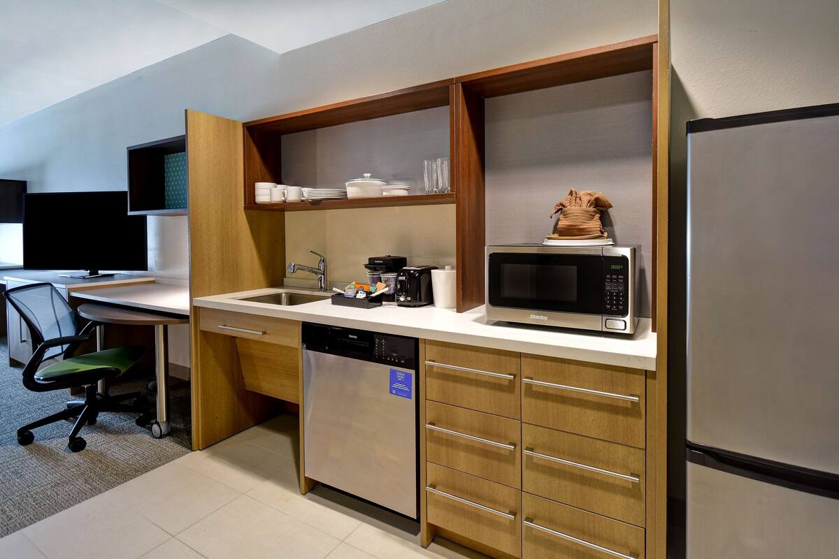 A compact kitchen with a dishwasher, microwave, and a small refrigerator.
