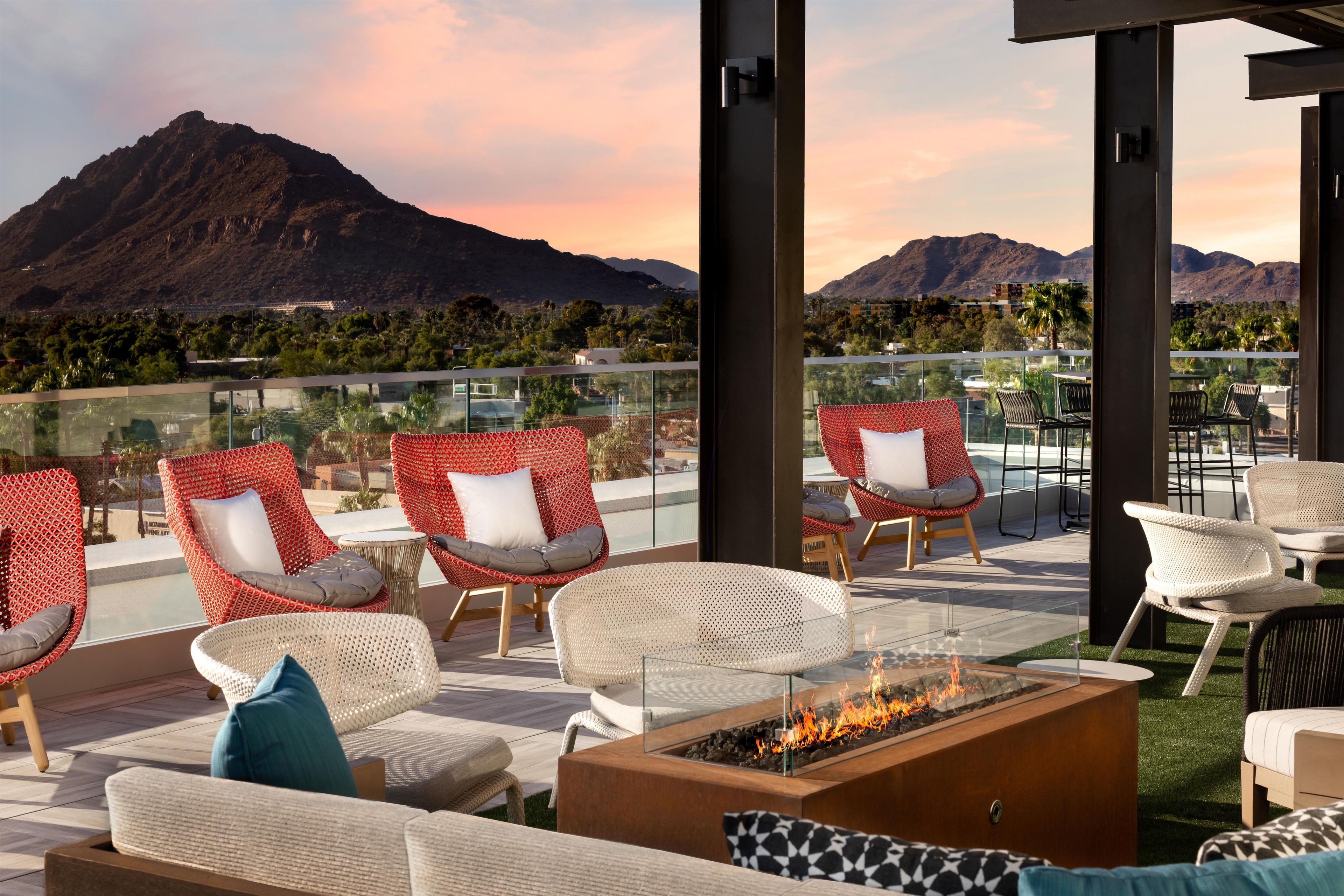 A rooftop terrace with outdoor seating, a fire feature, and a mountain view.