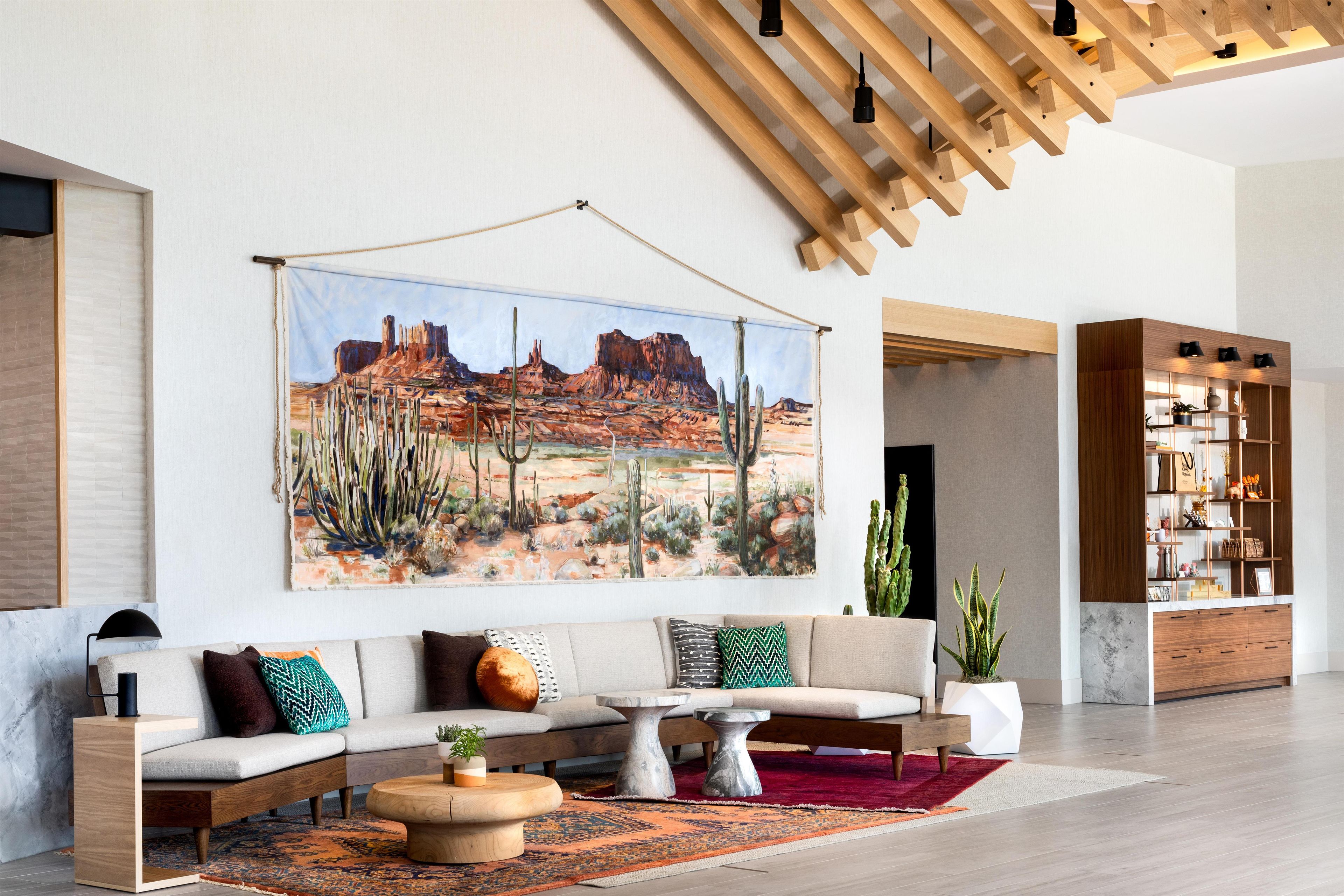 A modern living room with a sofa set, coffee table, and a large desert landscape painting.
