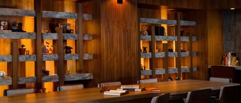 A conference room with a long table, multiple chairs, and shelves with various items.
