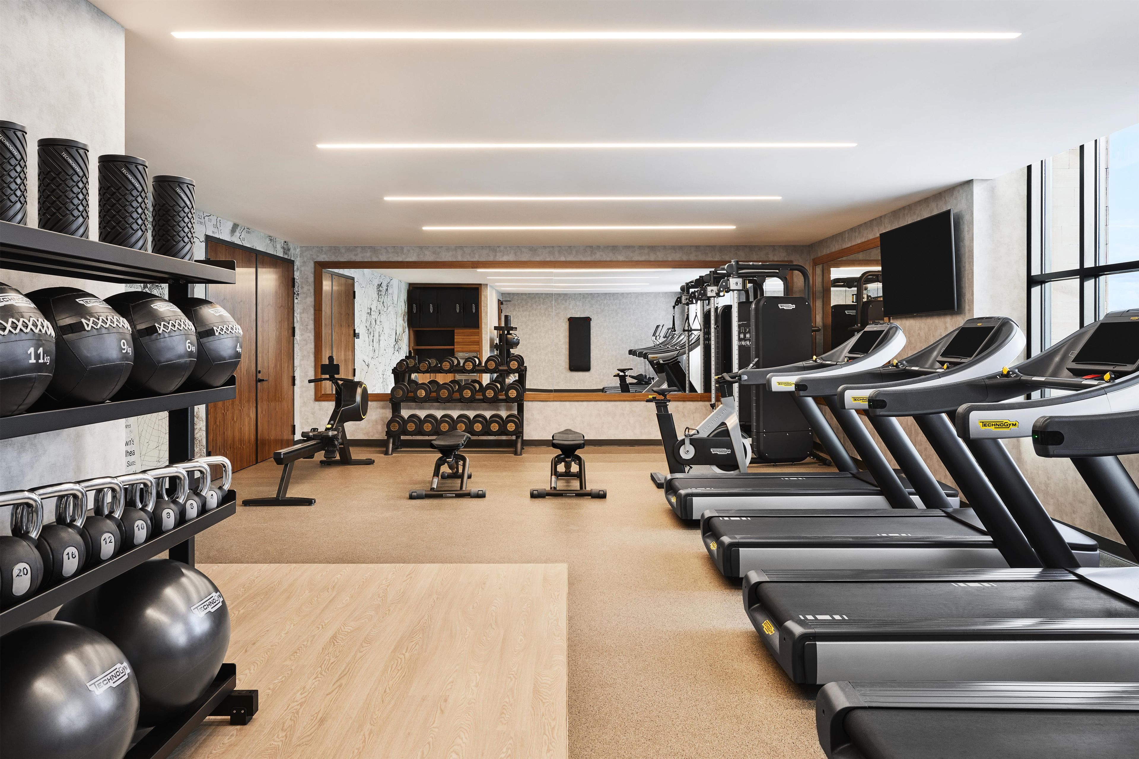 Une salle de sport équipée de tapis de course, d’appareils de musculation et de poids libres.