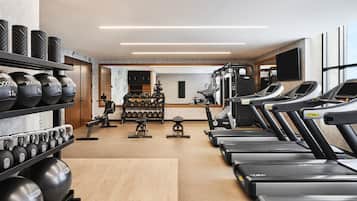 Une salle de sport équipée de tapis de course, d’appareils de musculation et de poids libres.