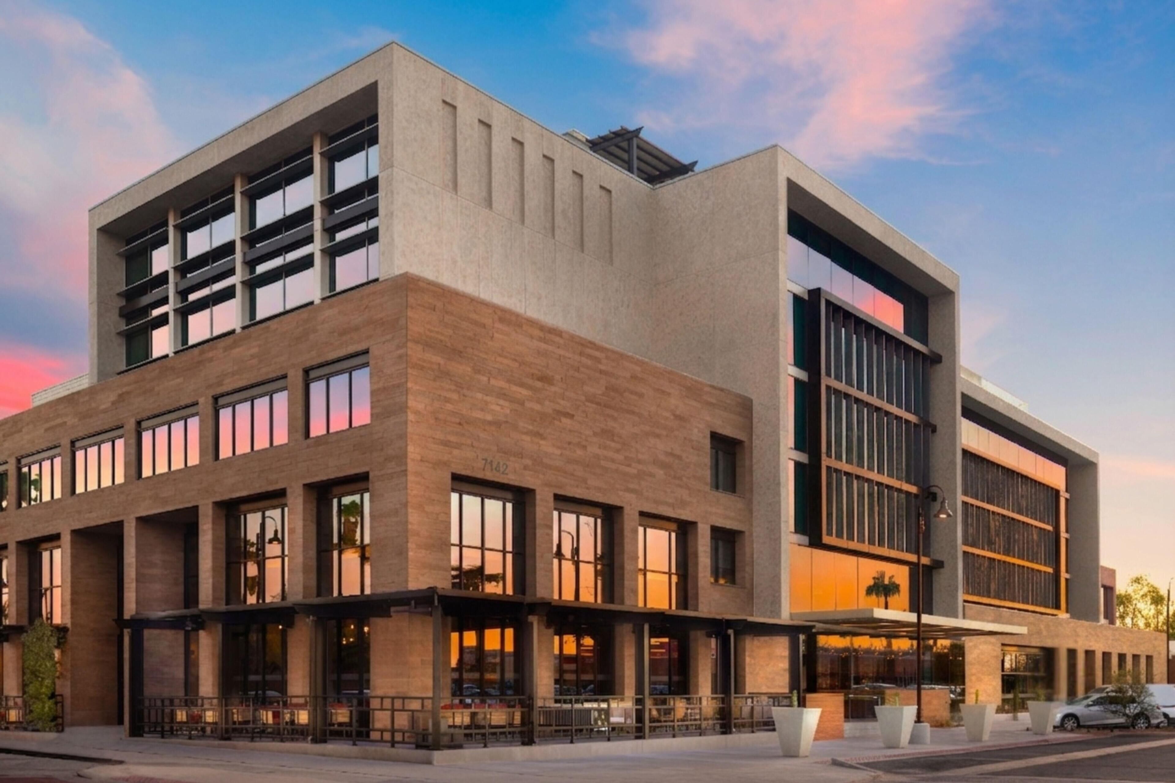 A modern building with a flat roof, large windows, and a mix of brick and concrete materials.