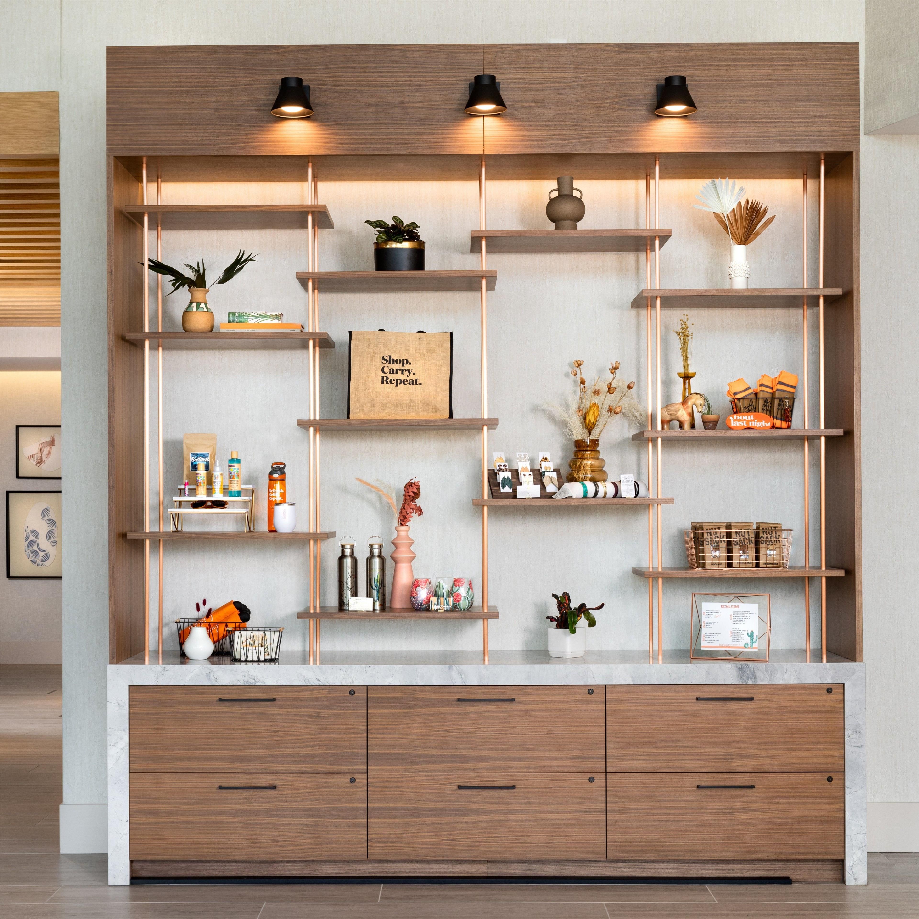 A modern interior with wooden shelving, decorative items, and a sign that reads 'Shop. Carry. Repeat.'